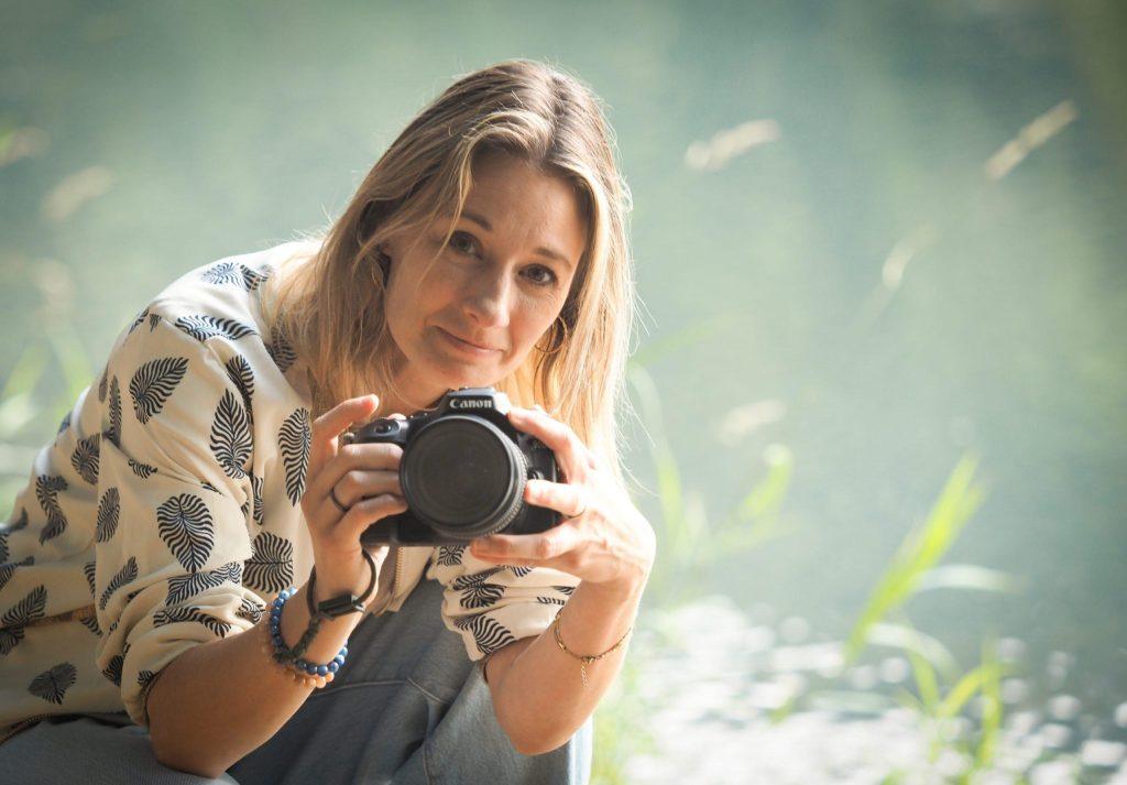 Lise, photographe à Neufchâteau, tenant son appareil photo en extérieur