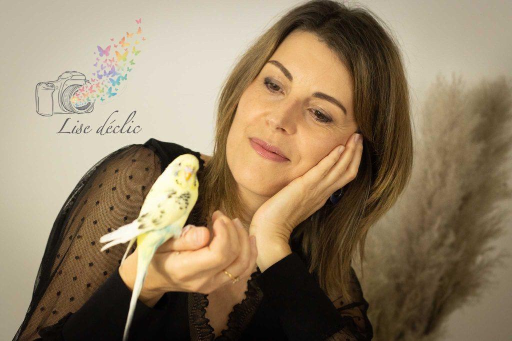 Portrait doux d’une femme tenant une perruche en studio – séance photo confiance en soi Lise Déclic