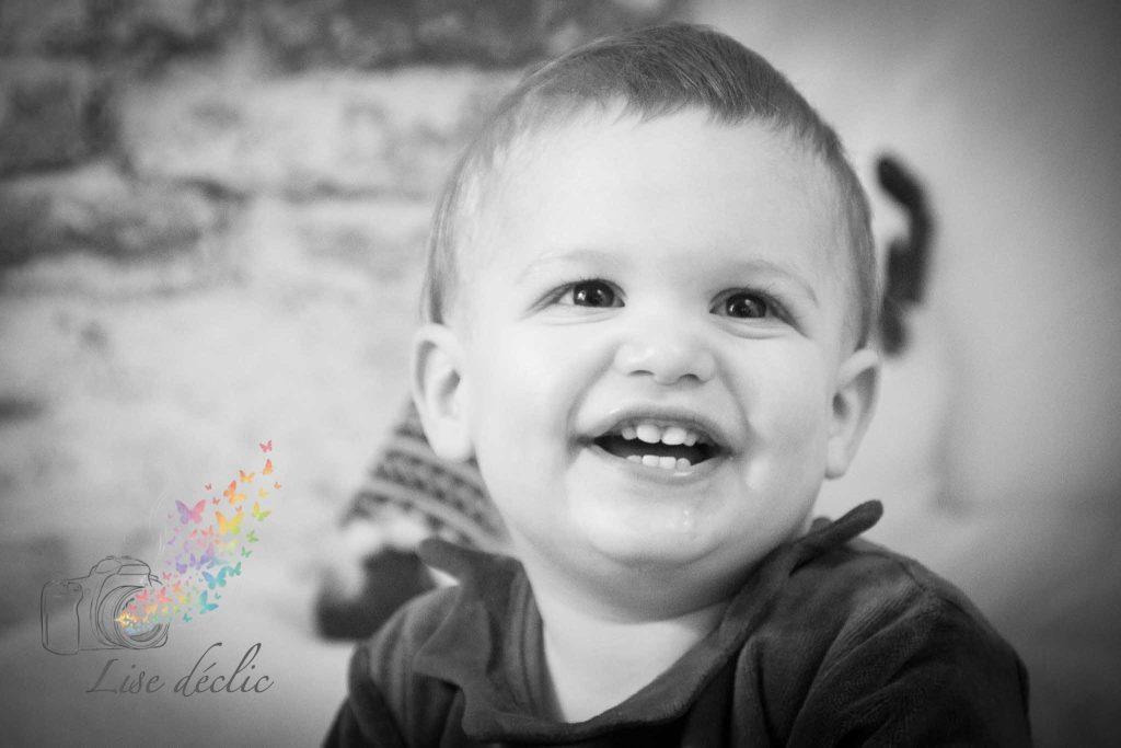Portrait en noir et blanc d’un bébé souriant lors d’une mini séance photo de Noël