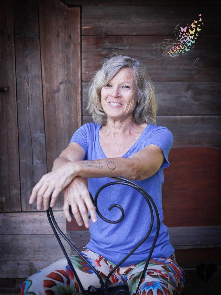 Portrait naturel en extérieur d’une femme souriante devant un mur en bois – séance photo confiance en soi Lise Déclic