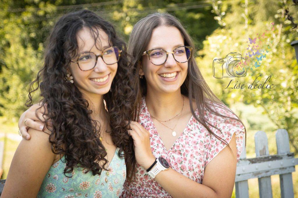 Deux jeunes femmes souriantes enlacées lors d’une séance photo authentique en extérieur dans un parc