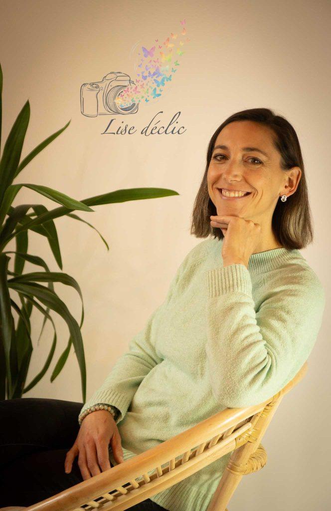 Portrait en studio d’une femme souriante assise sur une chaise en rotin – séance photo confiance en soi Lise Déclic