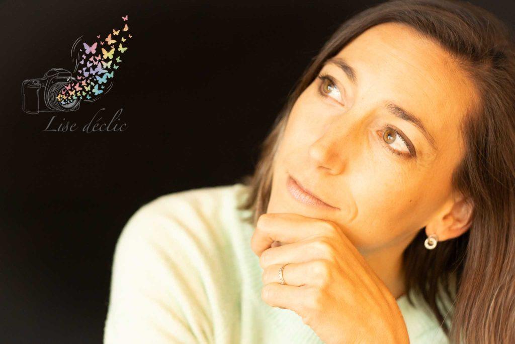 Portrait en studio d’une femme au regard tourné vers la lumière sur fond noir – séance photo confiance en soi Lise Déclic