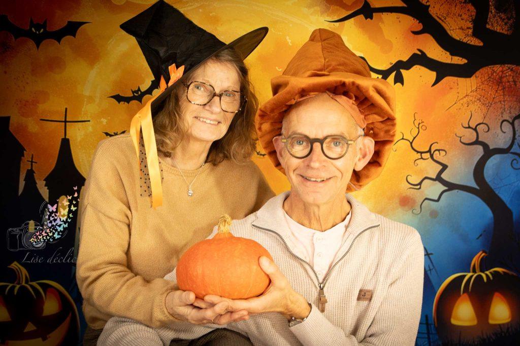 Couple senior souriant déguisé pour Halloween tenant une citrouille lors d’une mini séance photo à thème