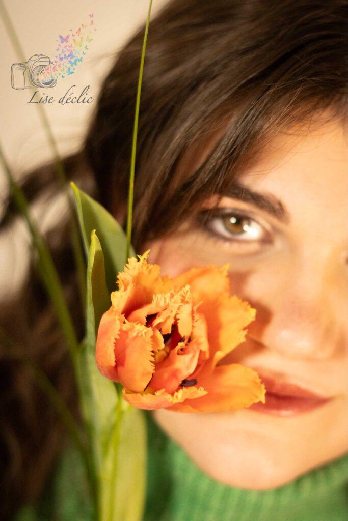 Gros plan sur un visage féminin avec une fleur orange en premier plan